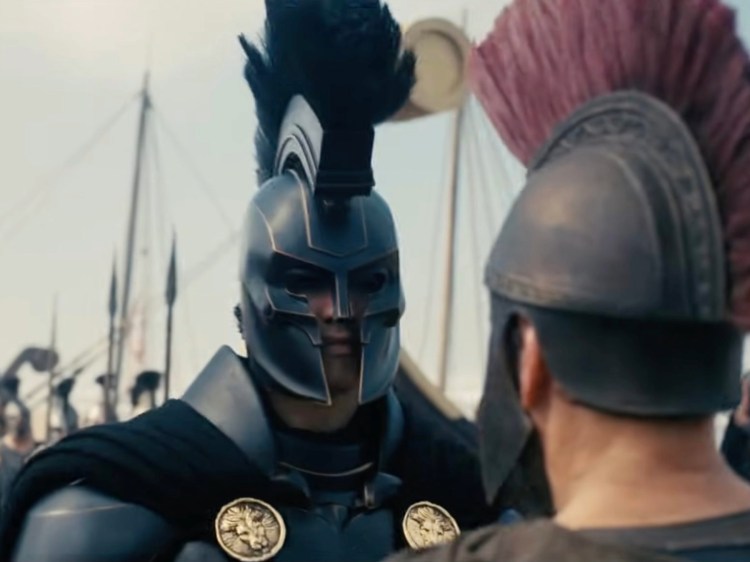 Agamemnon, dressed in full black armour, talking to Odysseus - a still from Christopher Nolan's The Odyssey. © 2026 Universal Pictures